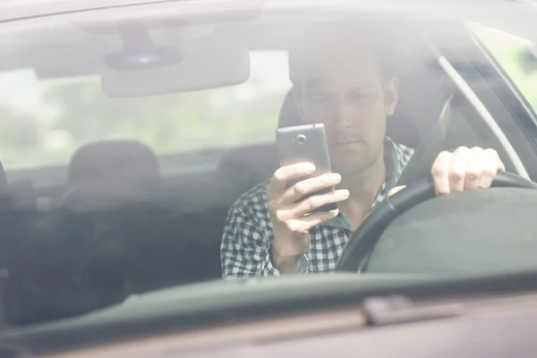 Mann benutzt Handy während Autofahrt Stockbild
