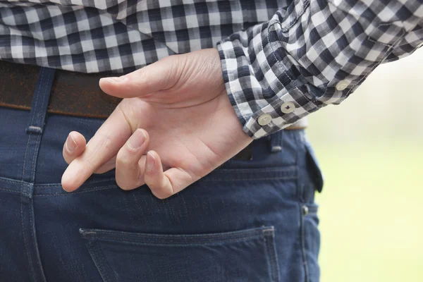 Mann drückt hinten die Daumen Stockbild