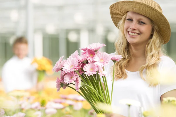 Jonge vrouw werkt en een tuinderij bij de bloemen Gerbera — Foto de Stock