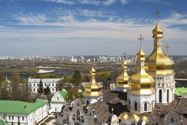 Tipo di cupola d'oro della cattedrale Uspensky del Kiev Pechersk Lavra in primo piano, il fiume Dnepr e Kiev all'orizzonte . — Foto Stock