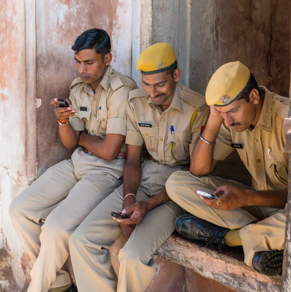 Amber fort, Indien - 27. September 2014: Drei Sicherheitsleute der Polizei sitzen am Eingang des amber fort und spielen mit ihren Mobiltelefonen lizenzfreie Stockbilder