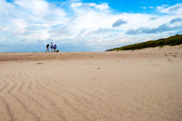 Praia de areia e três silhuetas remotas Imagens De Bancos De Imagens