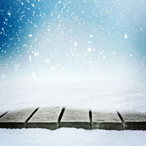 Mesa de madeira no snowdrift e neve folling sobre o céu de inverno Imagem De Stock