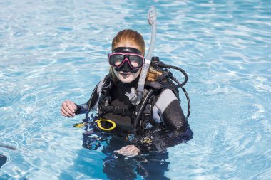 Dalgıcın dalgıç maskesiyle kameraya baktığı bir havuzda dalış eğitimi.