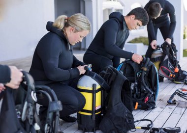 Bir grup scuba dalgıcı toplanıp aletlerini kontrol ediyor..