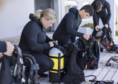 A group of scuba divers kitting up and checking their gear. clipart