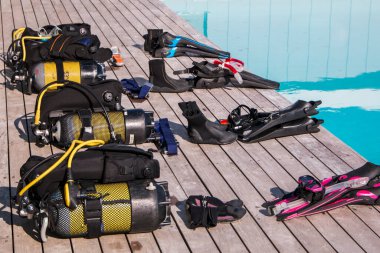 Scuba diving gear laying next to a training pool ready to be used clipart