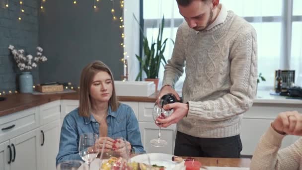 Close-up van een blanke mensenhanden die twee glazen vasthouden en er rode wijn in gieten. — Stockvideo