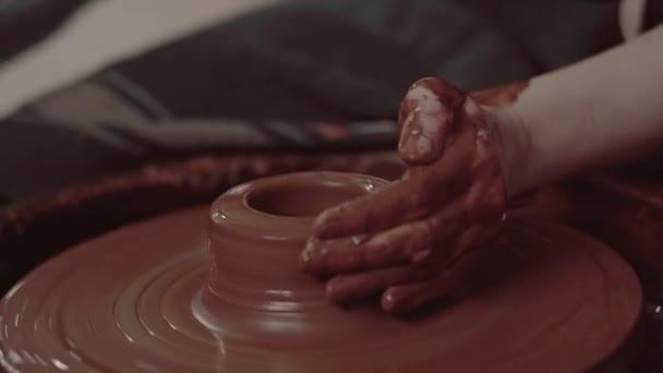 Close-up shot van een meester vrouwelijke pottenbakker gieten natte klei in een kom op draaiende pottenbakkers wiel. — Stockvideo