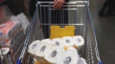 Sepetteki süpermarkette tuvalet kağıdı ruloları. Covid-19 Coronavirus salgınında mal alımı karantina altında..
