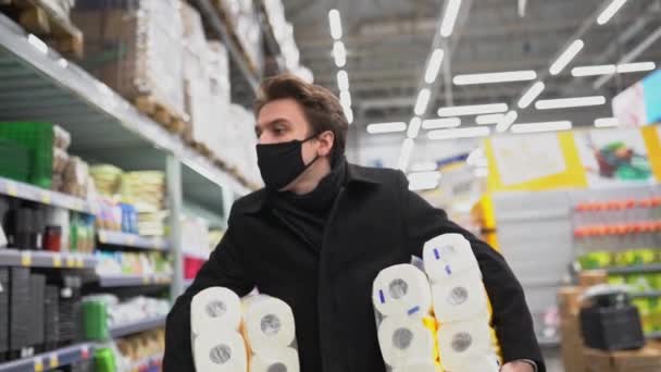 Orvosi maszkban sétáló férfi WC-papír bevásárlószatyorral a karantén alatt COVID-19 világjárvány 2019-2021 koronavírus karantén — Stock videók
