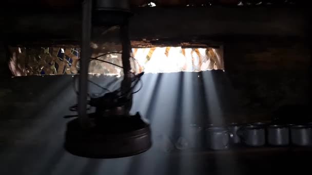 Drewniana ławka, w której pali się lampa naftowa. Światło z okna przenika do pokoju.. — Wideo stockowe