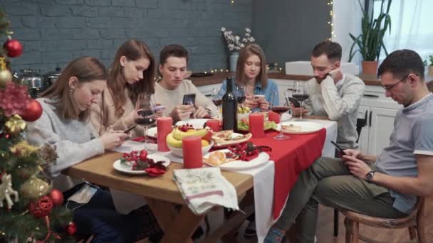 Grupo de jovens amigos aborrecidos aborrecidos usando telefones celulares lutando de tédio sentado juntos. Festa chata. Comunicação móvel — Vídeo de Stock