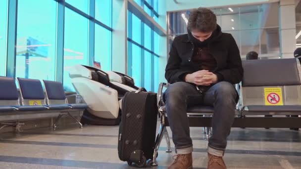 Homem usando máscara facial dormindo em um aeroporto durante a pandemia global. Covid-19 — Vídeo de Stock