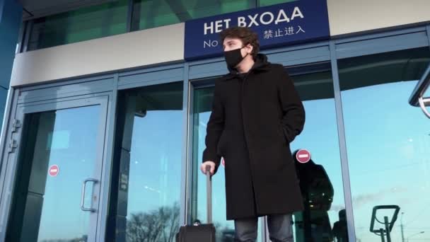 Egy férfi orvosi maszkban kisétál a reptérről.. — Stock videók