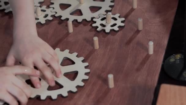 Primer plano de un niño que recoge engranajes de madera. — Vídeos de Stock