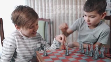 İki çocuk güzel bir odada satranç oynuyor.