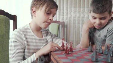 İki çocuk güzel bir odada satranç oynuyor.