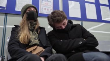 Maskeli bir adam uyuyakalır ve başını yabancı bir kadına yaslar. Hastalık belirtisi olarak yorgunluk. Salgında yüz koruması