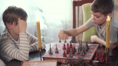 İki çocuk güzel bir odada satranç oynuyor.