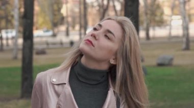 Üzgün, sarışın bir kız sokakta dikiliyor ve yüzünü çeviriyor..