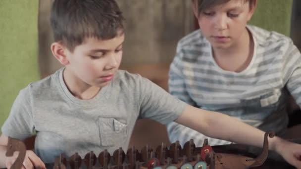 Två pojkar spelar en gammal Viking brädspel. Ett träskepp med krig — Stockvideo