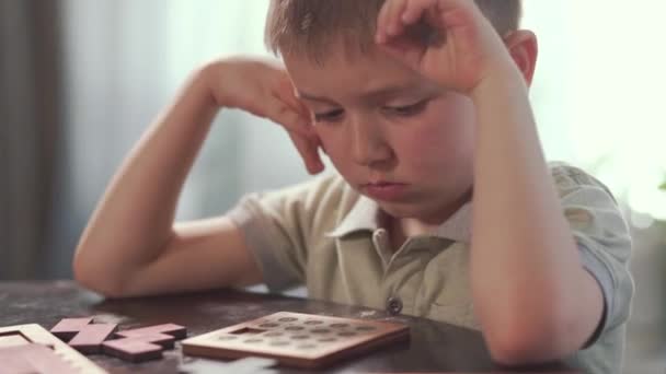 Das Kind bastelt am Tisch ein Holzpuzzle. Pädagogisches logisches Spielzeug für Kinder — Stockvideo