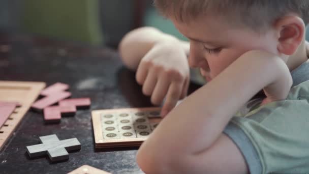 Dziecko układa przy stole drewniane puzzle. Edukacyjne zabawki logiczne dla dzieci — Wideo stockowe