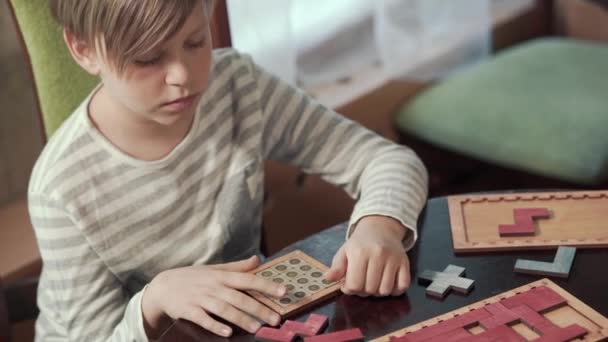 Il ragazzo raccoglie un puzzle mentre è seduto a un tavolo. — Video Stock