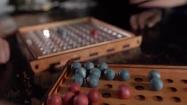 Board game with red and blue balls on the red playing field, black background — Stock Video