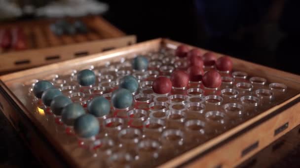 Bordspel met rode en blauwe ballen op het rode speelveld, zwarte achtergrond — Stockvideo