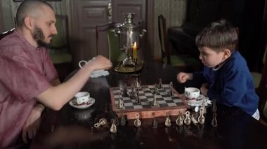 Yan görünüş, 6 'lı yaşların tatlı oğlu ve genç babası kapalı alanda satranç oynuyorlar..