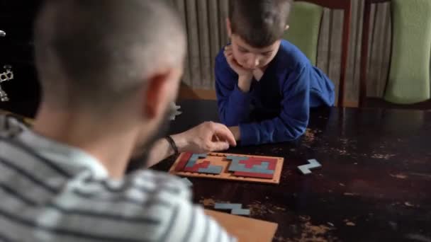 Father and his cute little kid assembling puzzle together. Father and his small boy having spare time at home. — Stock Video