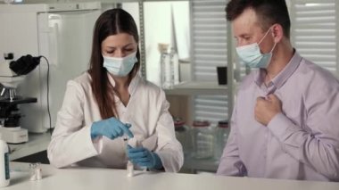 Kadın eller, lateks eldivenli hemşire elinde ilaç aşısıyla şırınga tutuyor.,