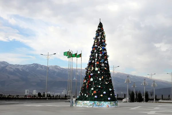 Christmas fir-tree on a square of Ashgabad and mountains as back — Stock Photo, Image
