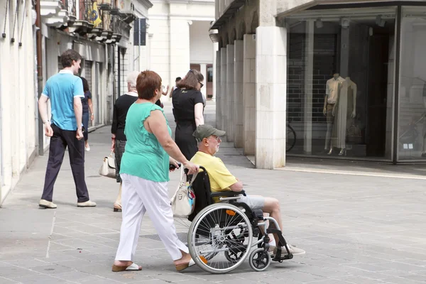 VENICE, MESTRE-June 29, 2014: Woman pushing a senior man in a wh — Stock Photo, Image