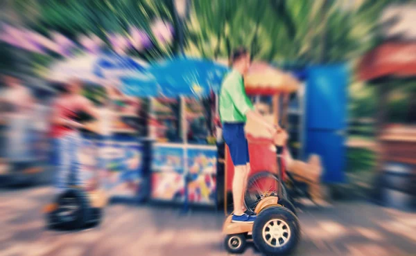 Abstrakt bakgrund. En ung man rider en Segway i parken. B — Stockfoto