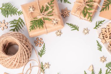 Beyaz arka planda, hediyeler dekoratif ahşap kar taneleri ile taze ladin dallarıyla süslenir. Noel veya kış kompozisyonu. Noel, kış, yeni yıl konsepti .