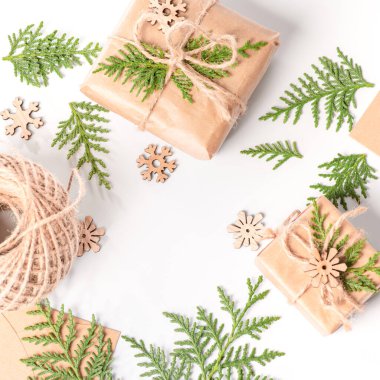 Beyaz arka planda, hediyeler dekoratif ahşap kar taneleri ile taze ladin dallarıyla süslenir. Noel veya kış kompozisyonu. Noel, kış, yeni yıl konsepti .