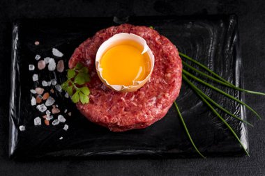 Yeşil soğan, yumurta sarısı ve tuzlu siyah bir seramik tahtada tartar..