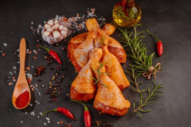 Kırmızı biberiye, biberiye ve baharatlı koyu bir arka planda tavuk budu. Tavuk budu..