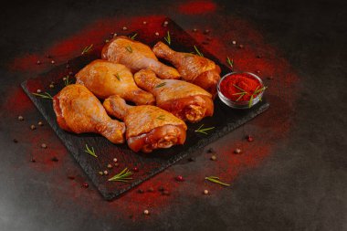 Tavuk budu. Kırmızı biber, biberiye ve baharatlı koyu bir arka planda tavuk budu..