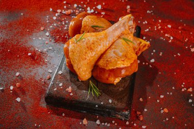 Kırmızı biberiye, biberiye ve baharatlı koyu bir arka planda tavuk budu. Tavuk budu.. .