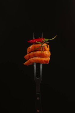 Siyah arka planda kırmızı biberli çatallı tavuk filetosu..