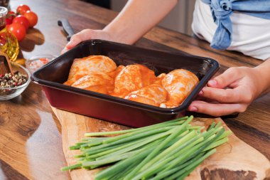 Mutfaktaki kız ızgara için marine edilmiş tavuk budu hazırlıyor..