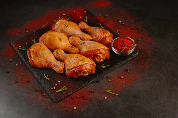 Tavuk budu. Kırmızı biber, biberiye ve baharatlı koyu bir arka planda tavuk budu..