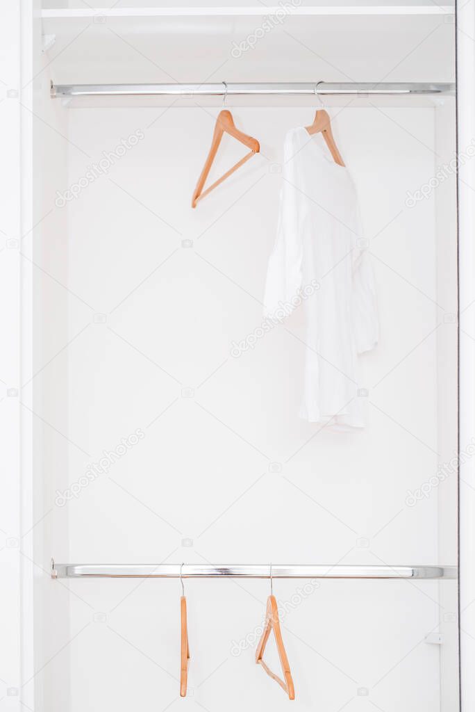 Modern wardrobe with one white T-shirt and empty ramps hanging in the wardrobe