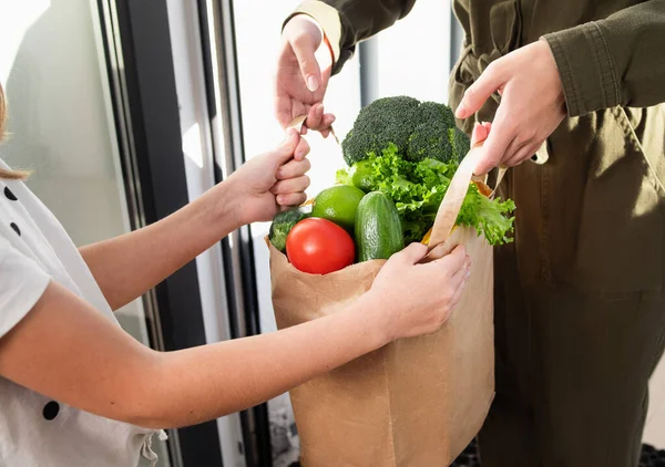 Home delivery concept. The girl receives a package of food at home.delivery food service at home.courier delivered order no name bag with food to cozy cottage.