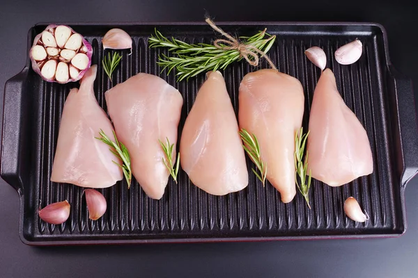Raw organic chicken breast on a iron grill pan a black background.Top view .Chicken pieces.Raw chicken steaks .