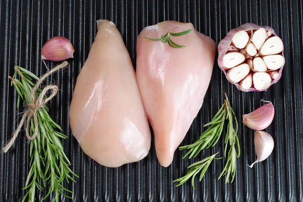 Raw organic chicken breast on a iron grill pan a black background.Top view .Chicken pieces.Raw chicken steaks .